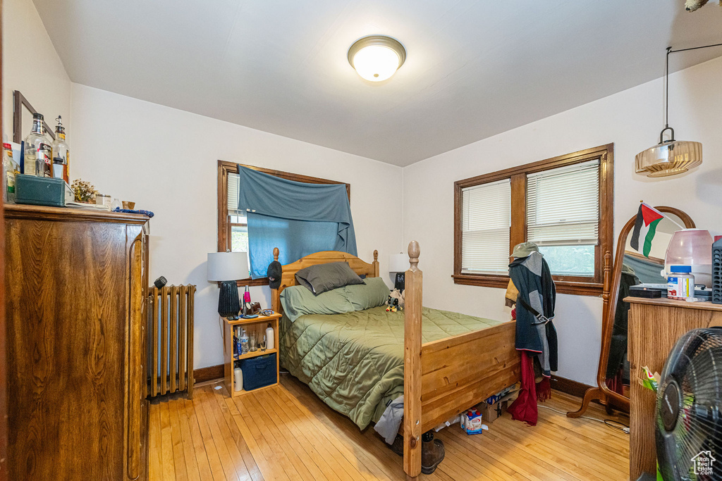 Bedroom featuring radiator heating unit, hardwood / wood-style flooring, and baseboards
