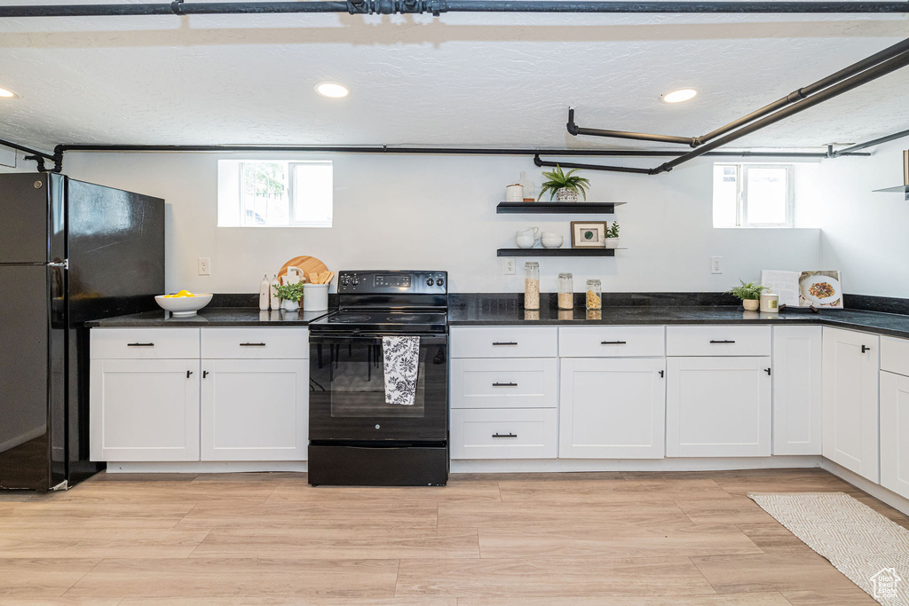 Kitchen featuring black appliances, recessed lighting, healthy amount of natural light, open shelves, and dark countertops