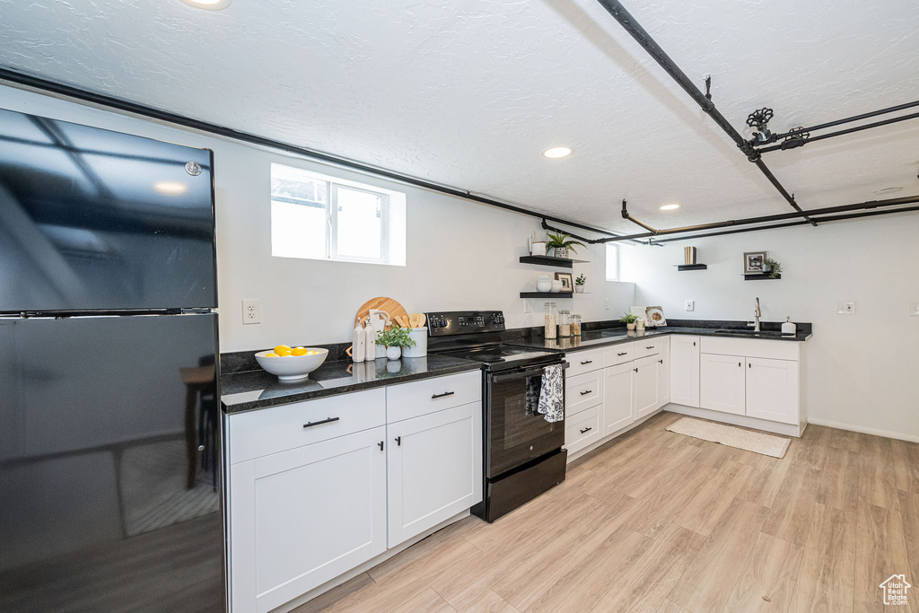 Kitchen featuring black appliances, white cabinetry, a sink, recessed lighting, and light wood-style flooring
