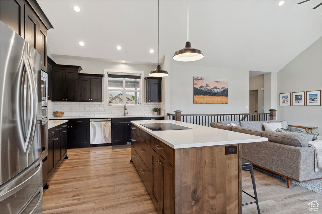 Kitchen with tasteful backsplash, a kitchen bar, open floor plan, a center island, and appliances with stainless steel finishes