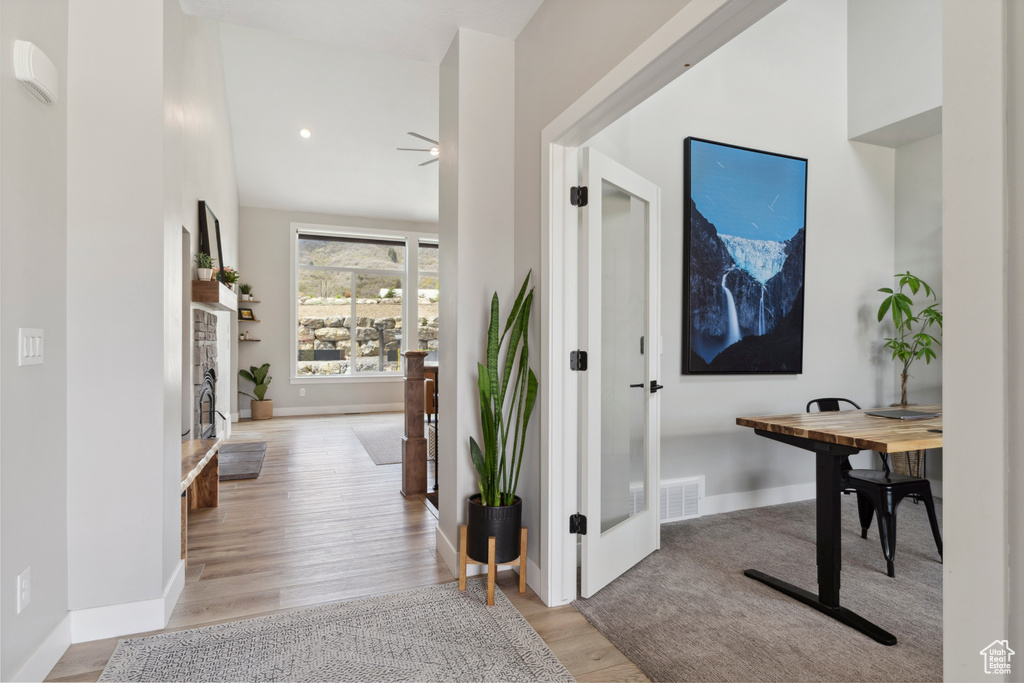 Hall featuring light wood finished floors, baseboards, and visible vents