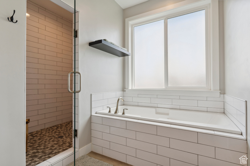 Full bathroom with a bath, a wealth of natural light, and a shower stall