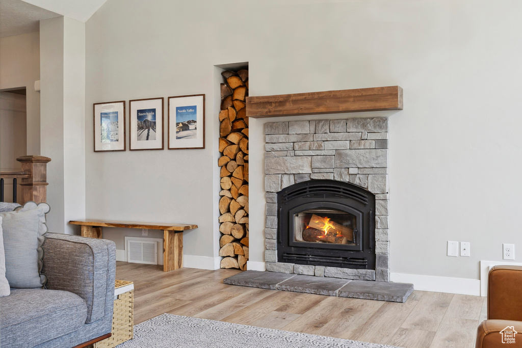 Detailed view of wood finished floors, a stone fireplace, and baseboards