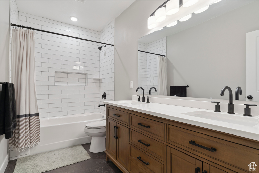 Bathroom featuring a sink, double vanity, toilet, and shower / bath combo