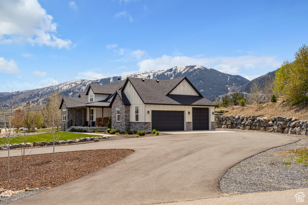 View of front of house featuring board and batten siding, driveway, a mountain view, an attached garage, and stone siding
