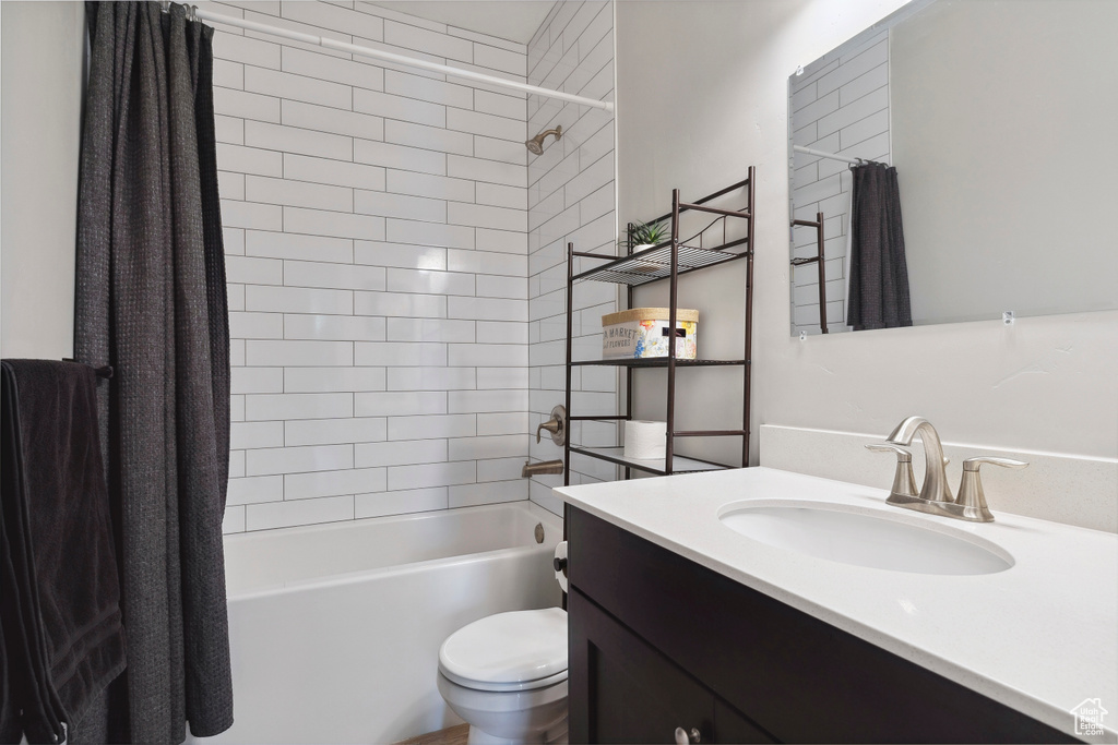 Bathroom featuring toilet, shower / tub combo with curtain, and vanity