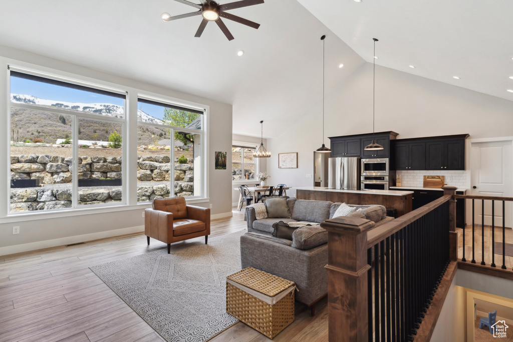 Living area featuring light wood finished floors, recessed lighting, ceiling fan, and high vaulted ceiling