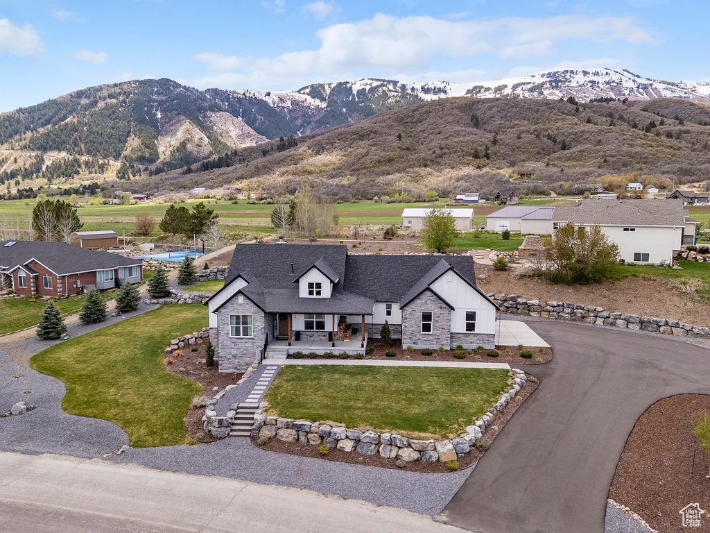 Exterior space with stone siding, a mountain view, a porch, and driveway