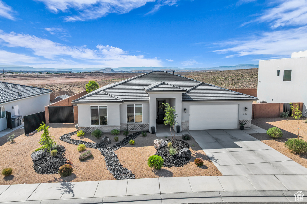 View of front facade featuring stucco siding, an attached garage, a mountain view, concrete driveway, and brick siding