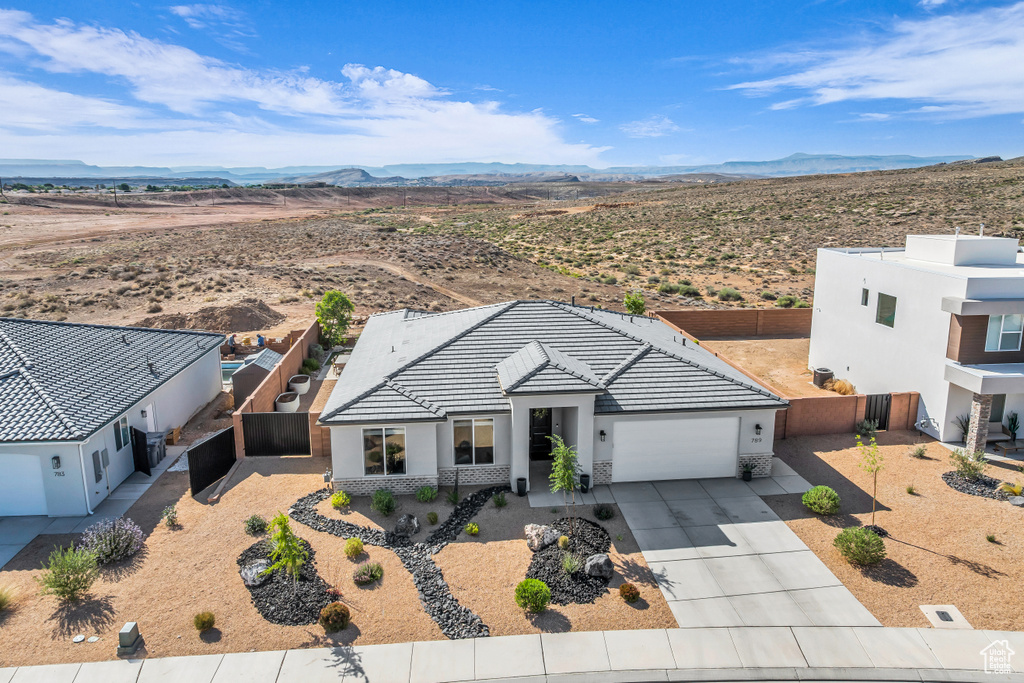View of front of house featuring an attached garage, concrete driveway, stucco siding, and a mountain view