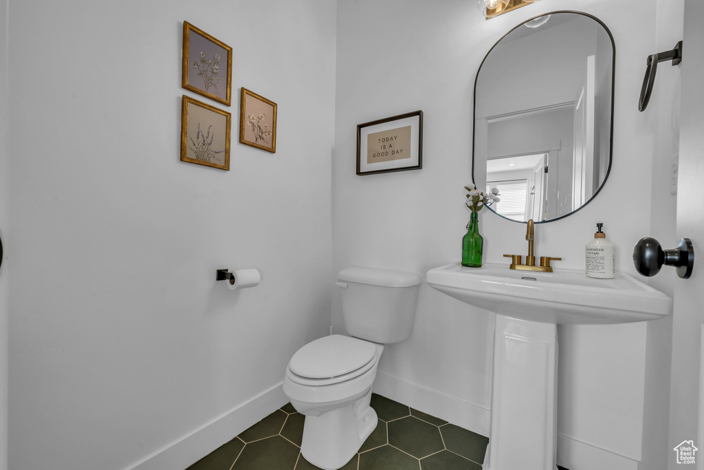 Half bath featuring toilet, baseboards, and tile patterned floors