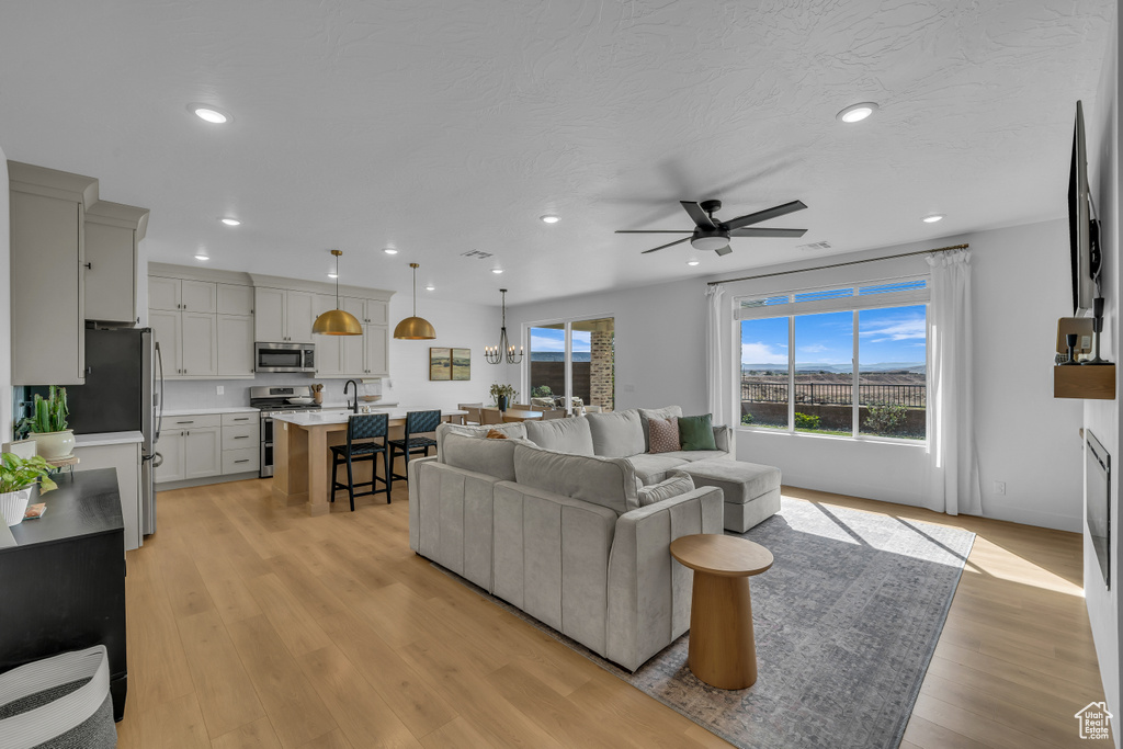 Living area featuring a ceiling fan, light wood-style floors, and recessed lighting
