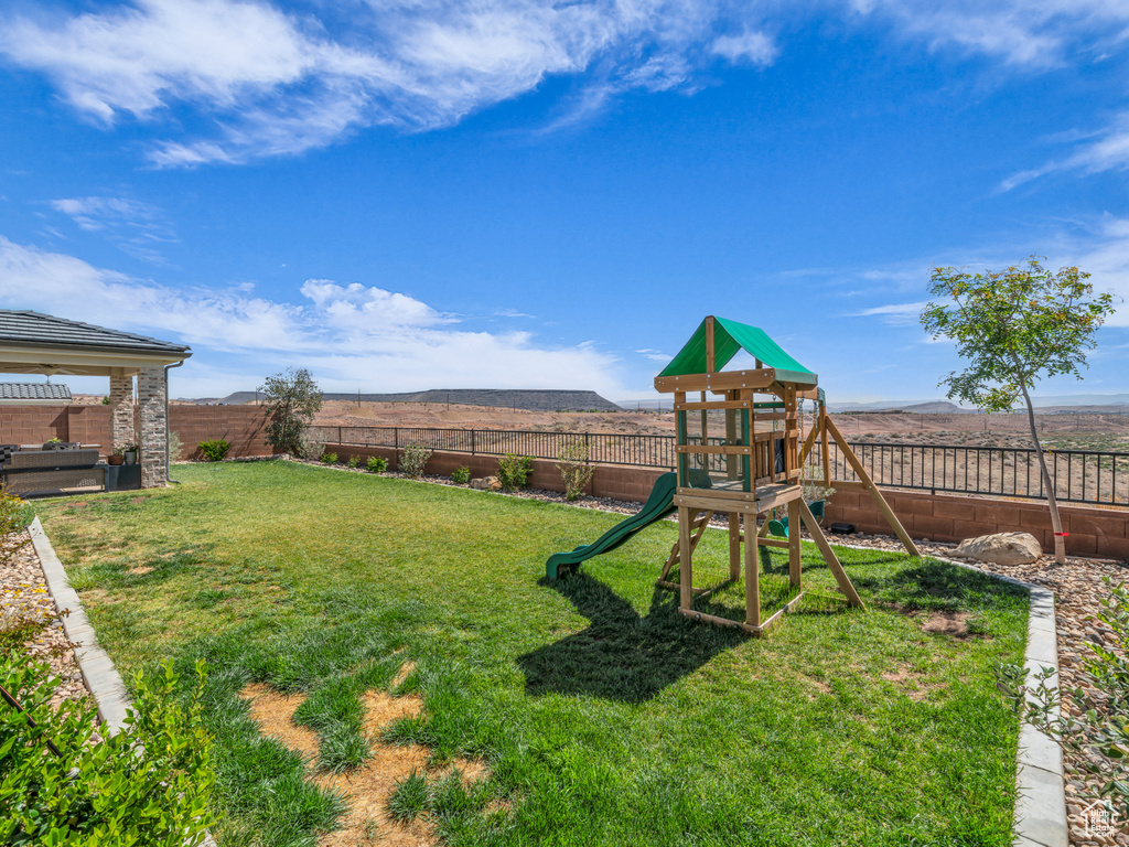 View of yard with a fenced backyard, a playground, and a mountain view