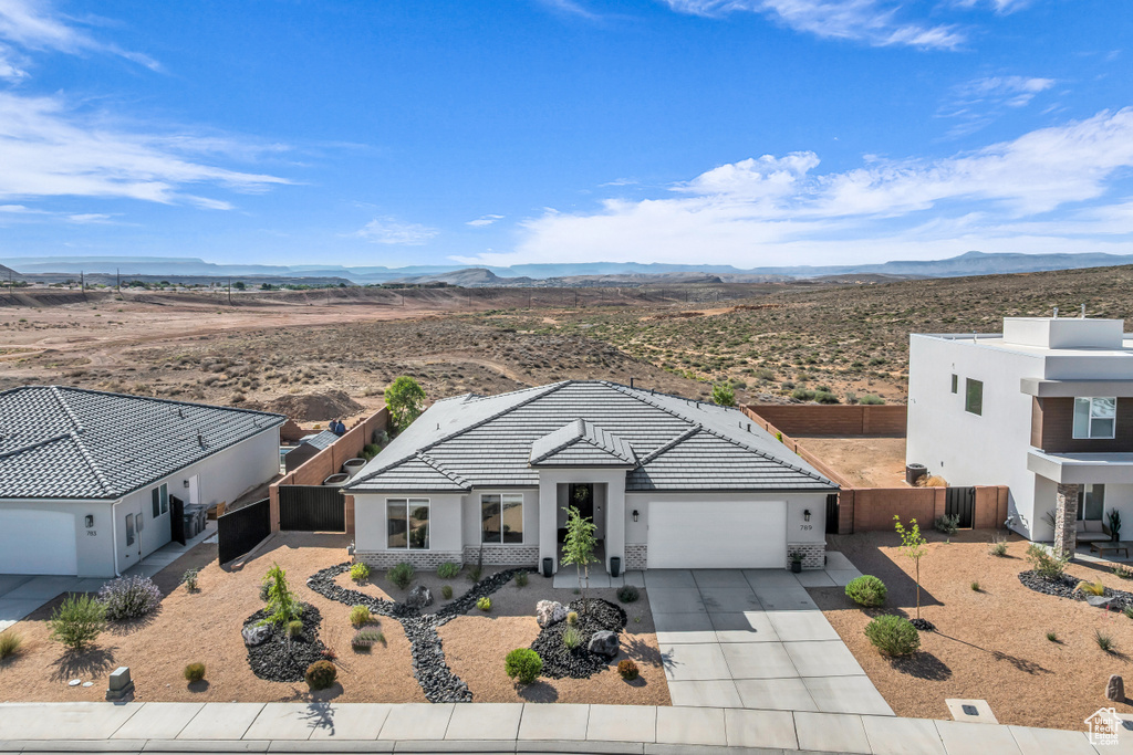 Single story home with an attached garage, concrete driveway, stucco siding, and a mountain view