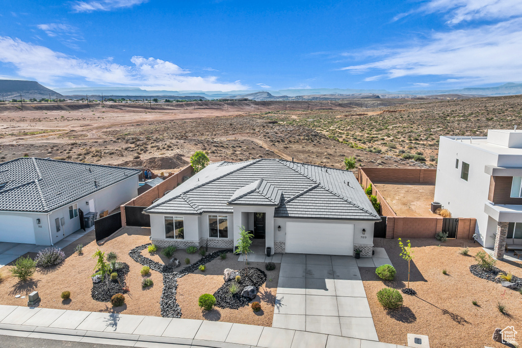 View of front of property featuring a garage, a mountain view, driveway, stucco siding, and a tile roof
