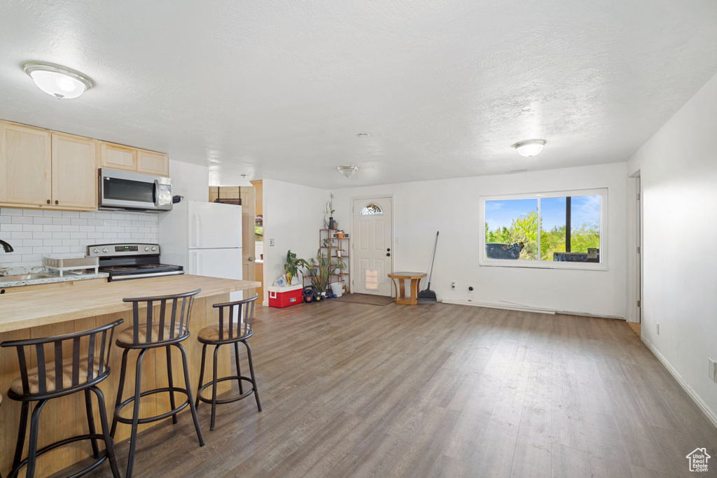 Kitchen with wooden counters, stainless steel appliances, wood finished floors, and a kitchen breakfast bar