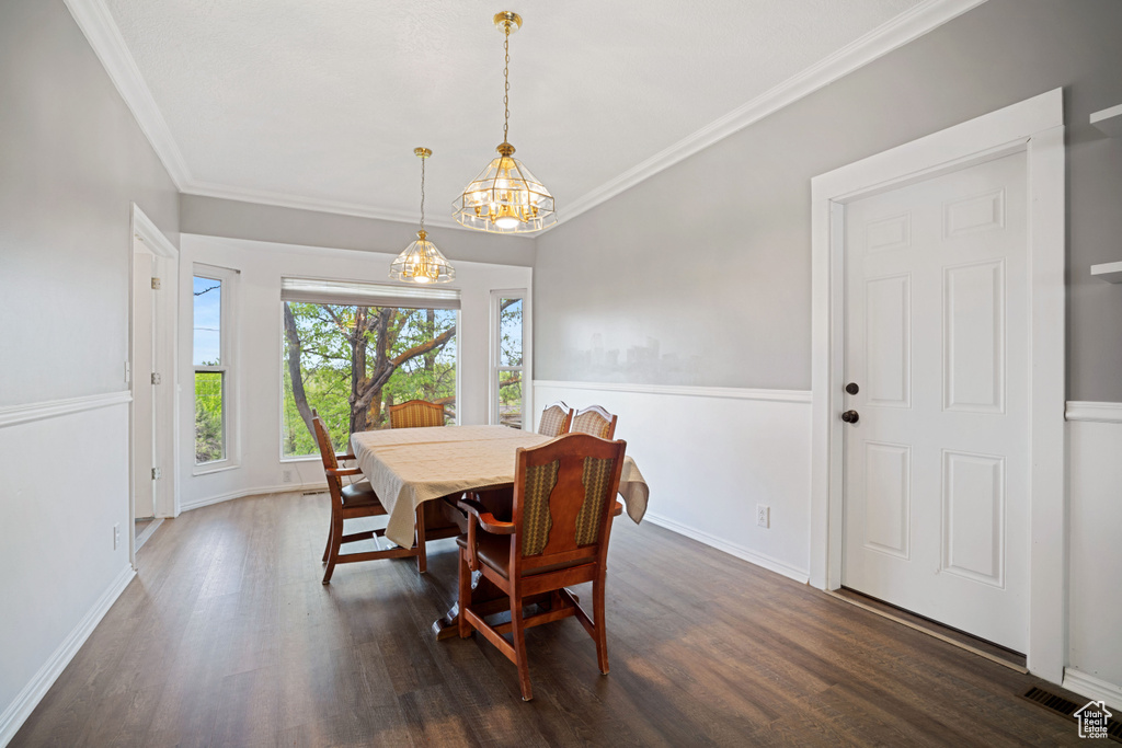 Dining area featuring baseboards, a chandelier, crown molding, and dark wood-style floors