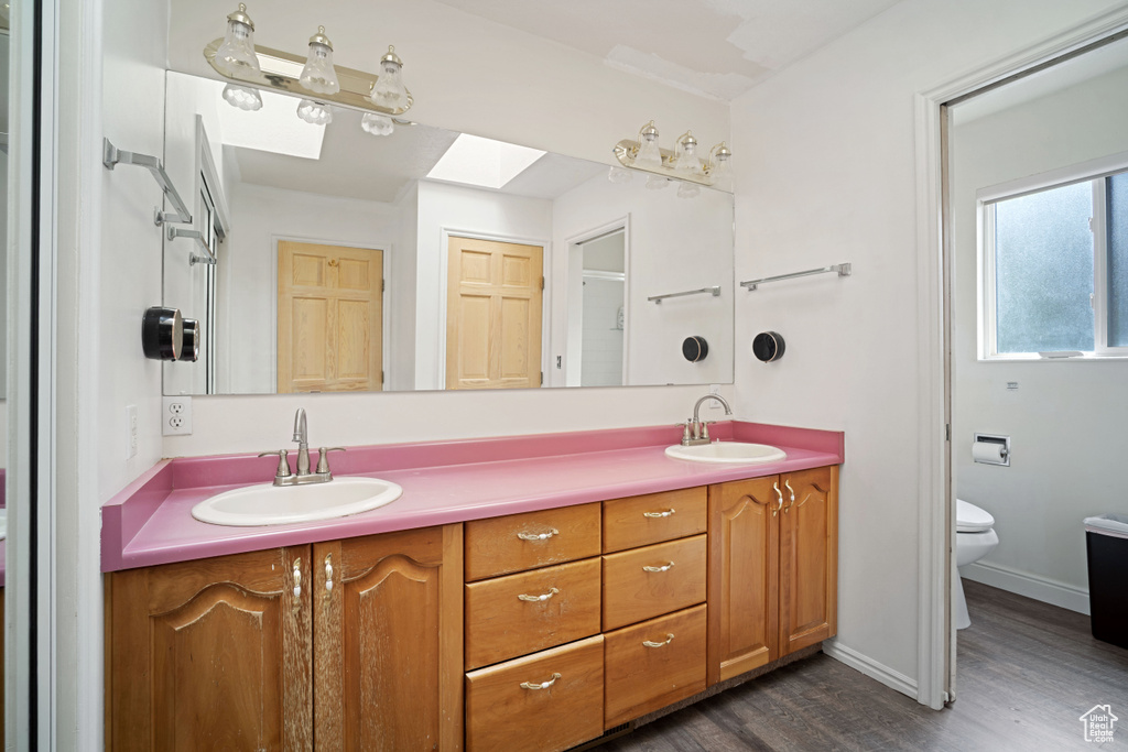 Bathroom featuring toilet, a skylight, double vanity, and a sink