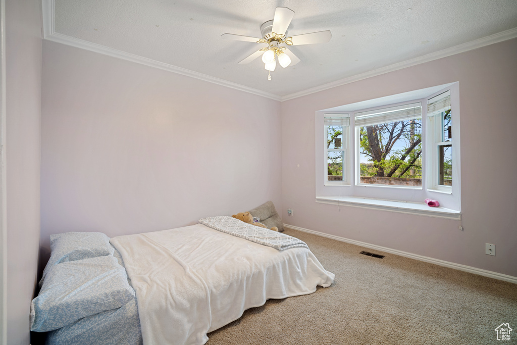 Carpeted bedroom featuring baseboards, ornamental molding, and visible vents
