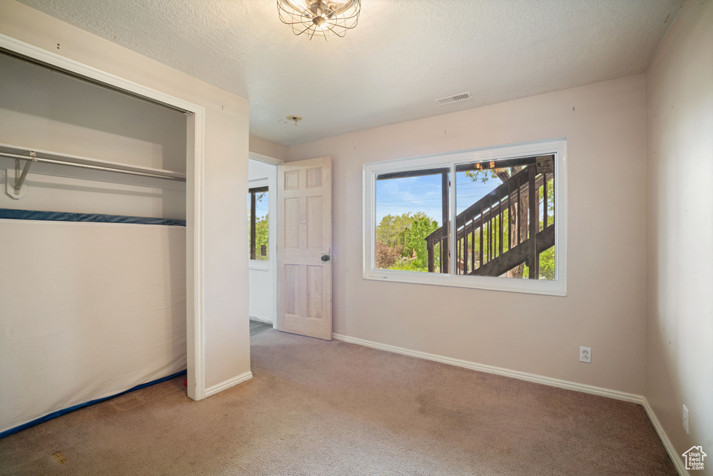 Unfurnished bedroom with a closet, a textured ceiling, baseboards, visible vents, and carpet floors
