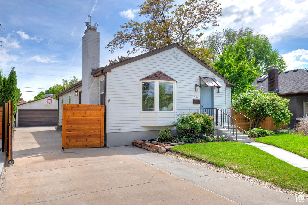 Bungalow with a chimney, an outdoor structure, and a garage