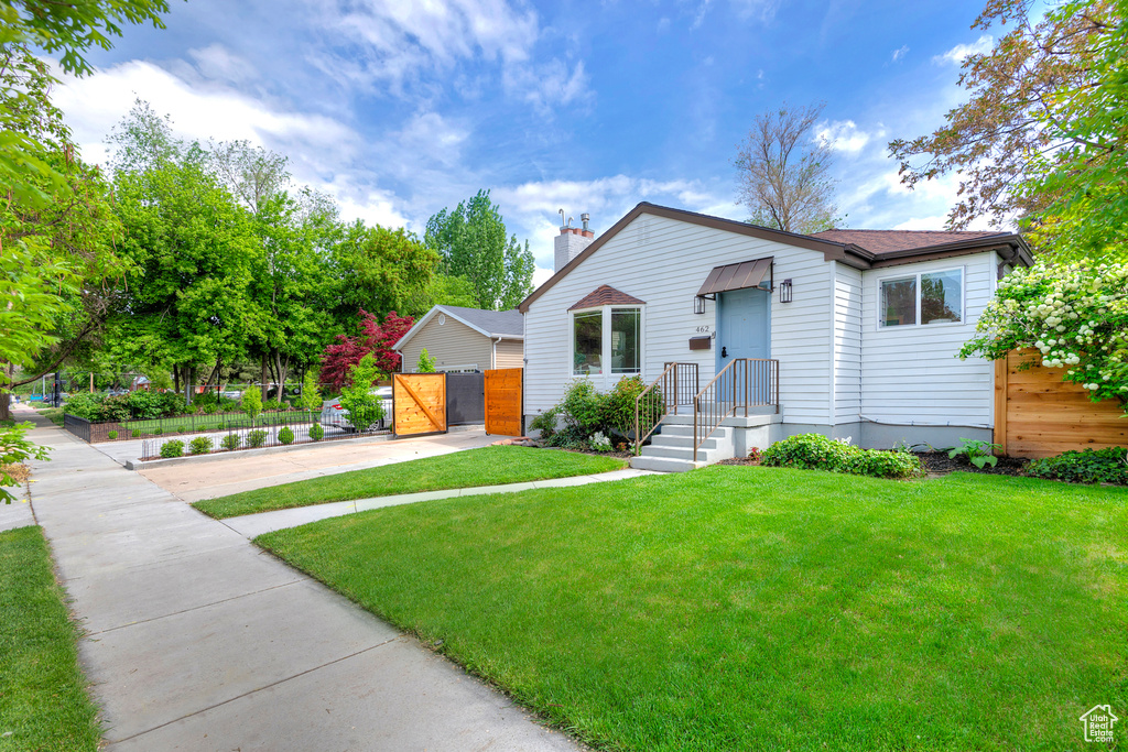 View of front of property featuring concrete driveway, a gate, a chimney, and a shingled roof