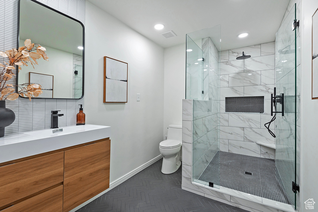 Full bathroom with baseboards, toilet, a marble finish shower, vanity, and recessed lighting
