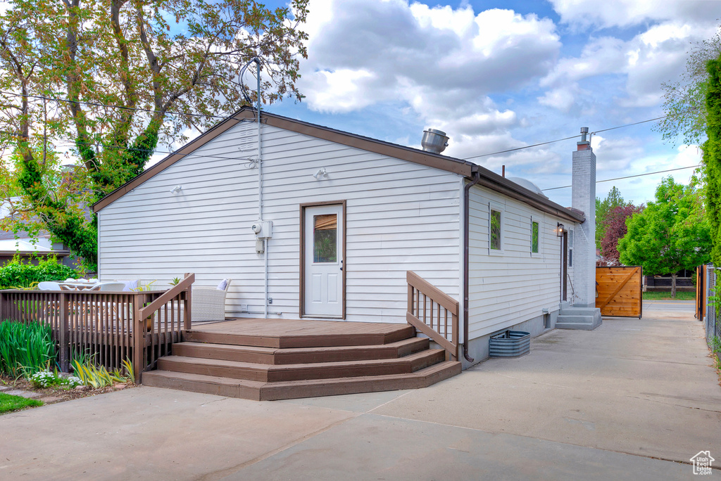 Back of house featuring entry steps, a deck, fence, and a patio