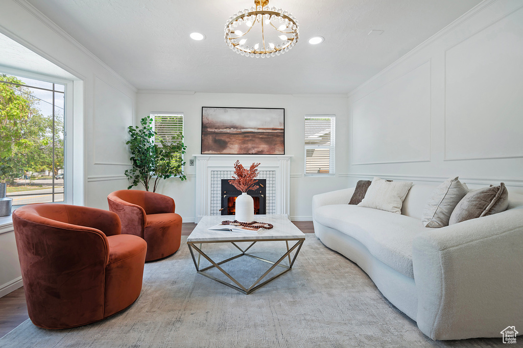 Living area with a chandelier, healthy amount of natural light, recessed lighting, a tiled fireplace, and crown molding