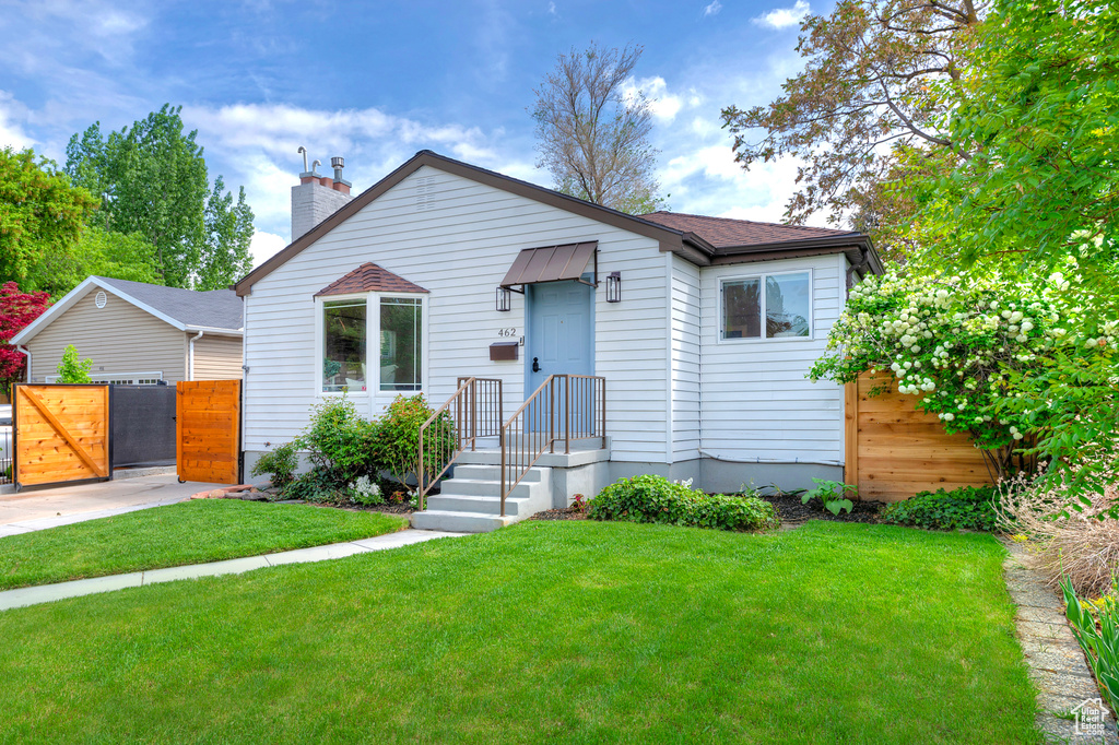 Bungalow featuring a gate, a chimney, and roof with shingles