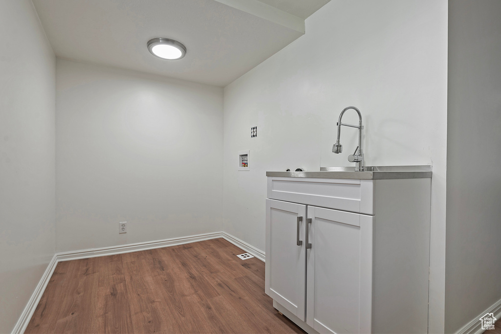 Laundry room featuring washer hookup, dark wood-style floors, cabinet space, and baseboards