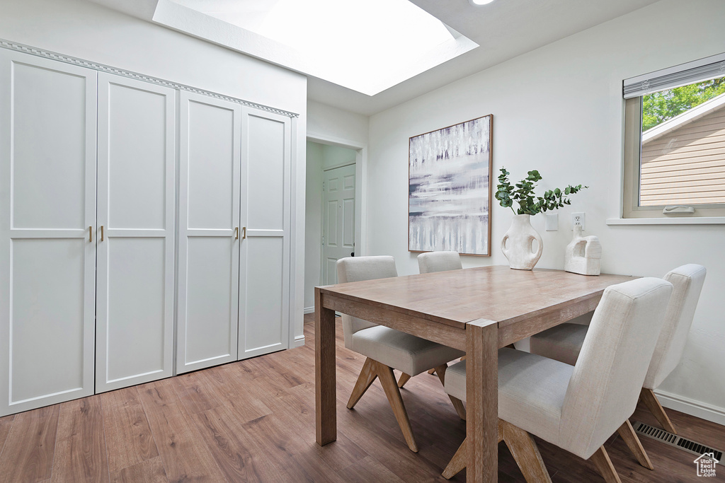 Dining area with a skylight, light wood-type flooring, and baseboards