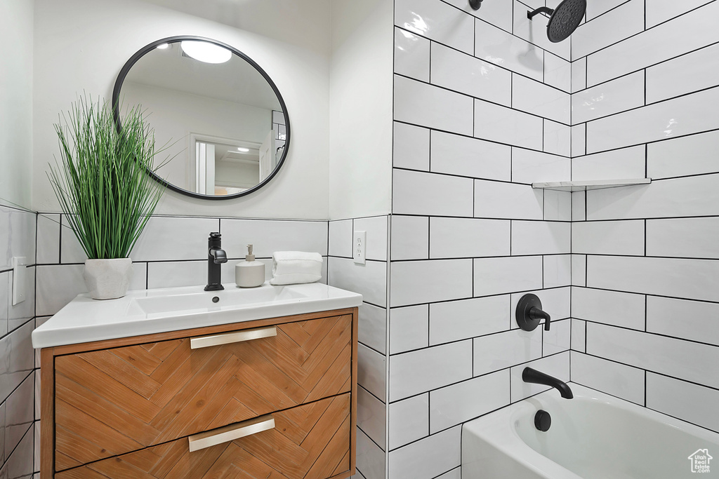 Full bathroom featuring tile walls,  shower combination, and vanity