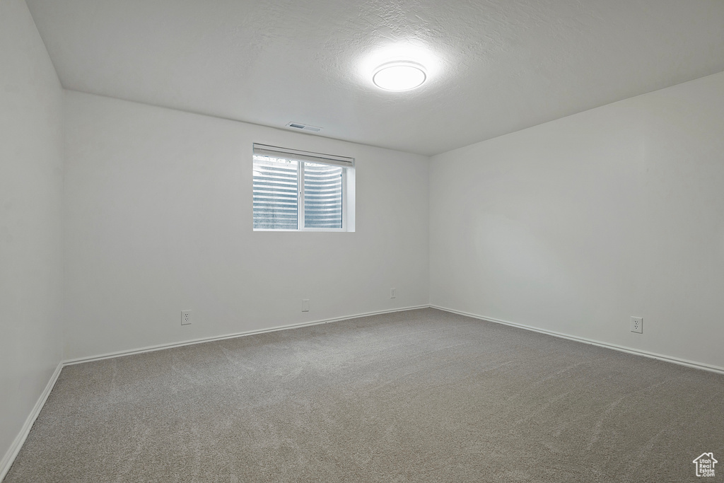Carpeted spare room featuring baseboards and a textured ceiling