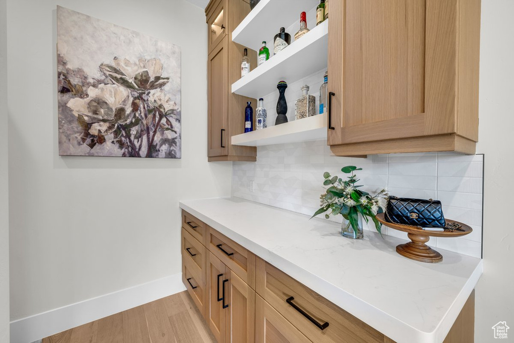 Bar featuring backsplash, baseboards, and light wood finished floors