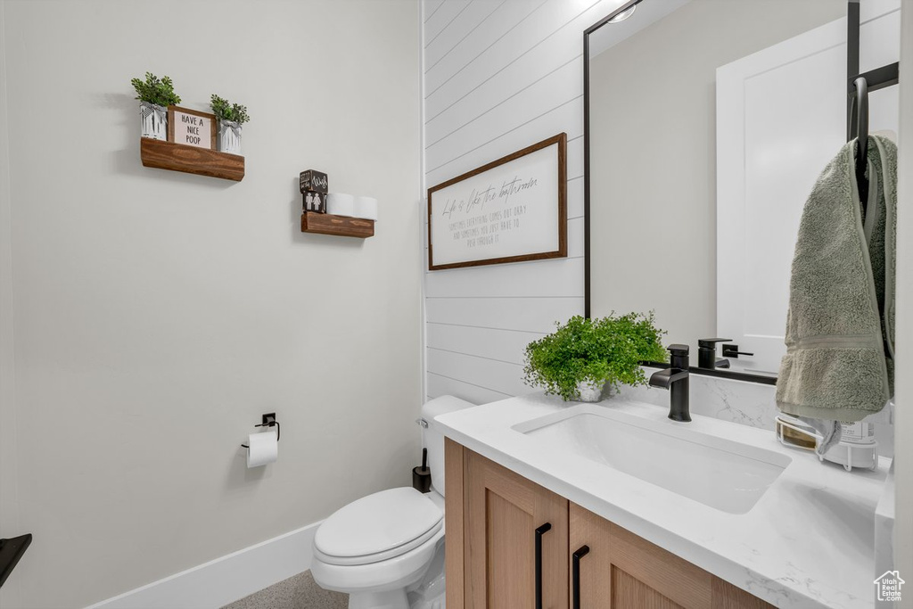 Bathroom with toilet, vanity, baseboards, and wooden walls