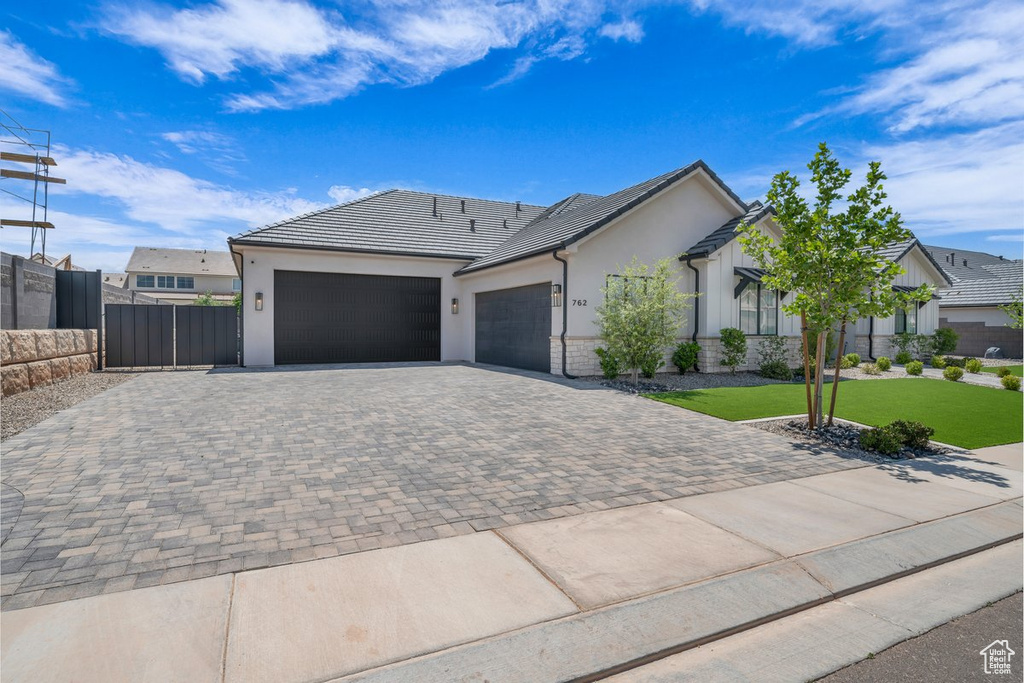 Ranch-style house featuring an attached garage, decorative driveway, and stucco siding