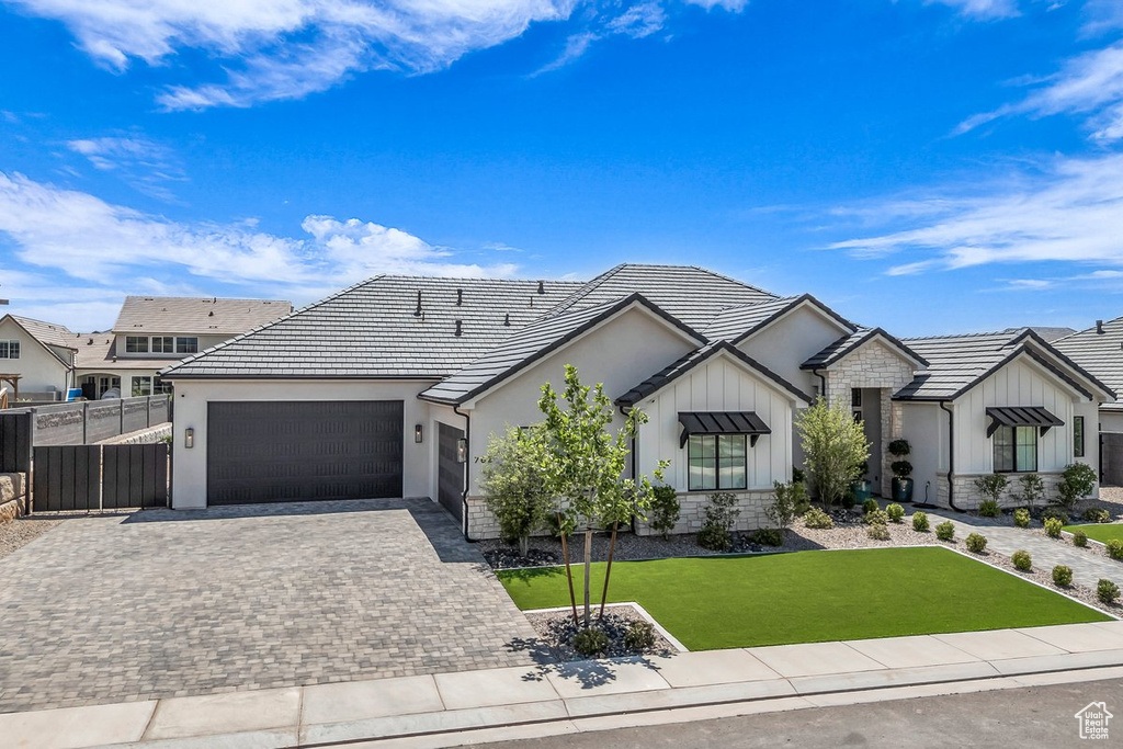 Ranch-style home featuring a garage, board and batten siding, decorative driveway, stone siding, and stucco siding