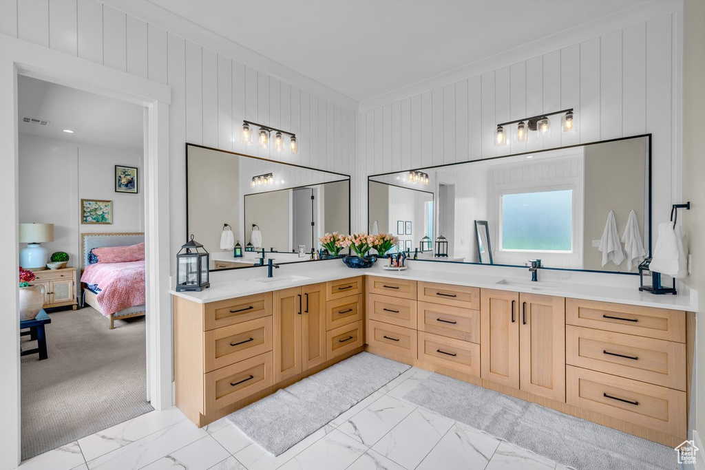 Ensuite bathroom featuring marble look tiles, double vanity, crown molding, and wooden walls