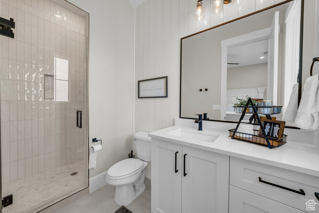 Bathroom with a stall shower, toilet, vanity, and tile patterned flooring