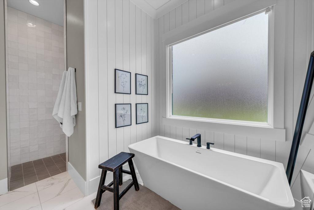 Bathroom with marble finish floors, a tile shower, and a freestanding bath