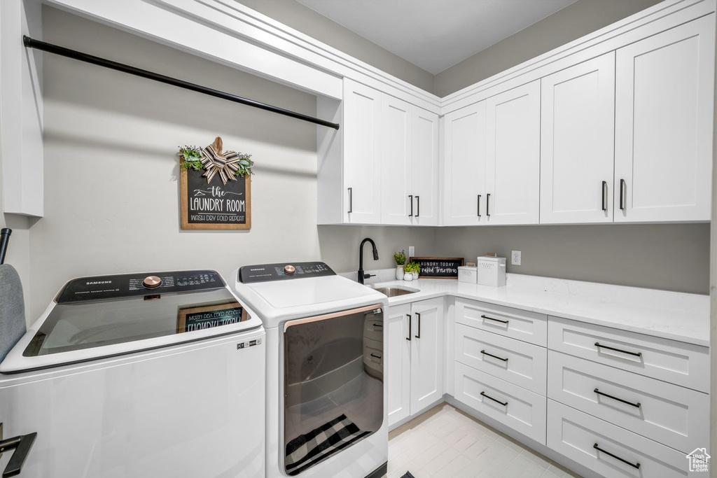 Laundry room with washing machine and clothes dryer, cabinet space, and light tile patterned floors