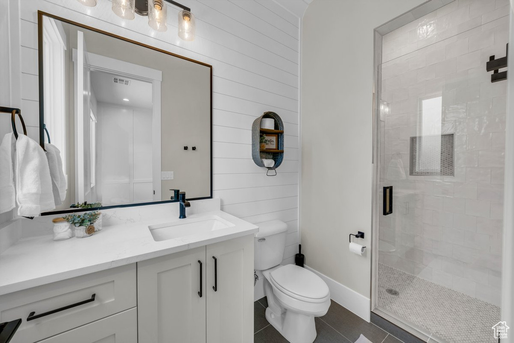 Bathroom featuring tile patterned floors, a shower stall, toilet, vanity, and wood walls