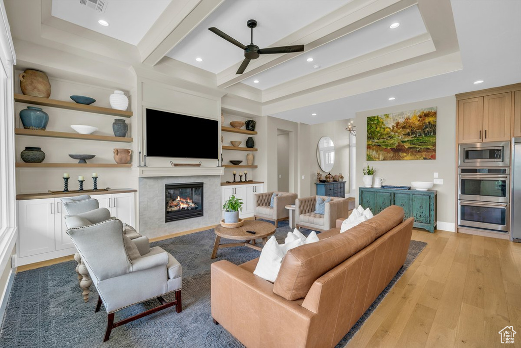 Living room featuring light wood-type flooring, ceiling fan, a premium fireplace, built in shelves, and recessed lighting
