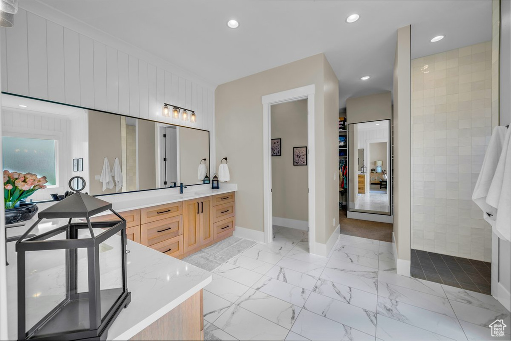 Bathroom featuring vanity, baseboards, a walk in closet, marble finish flooring, and recessed lighting
