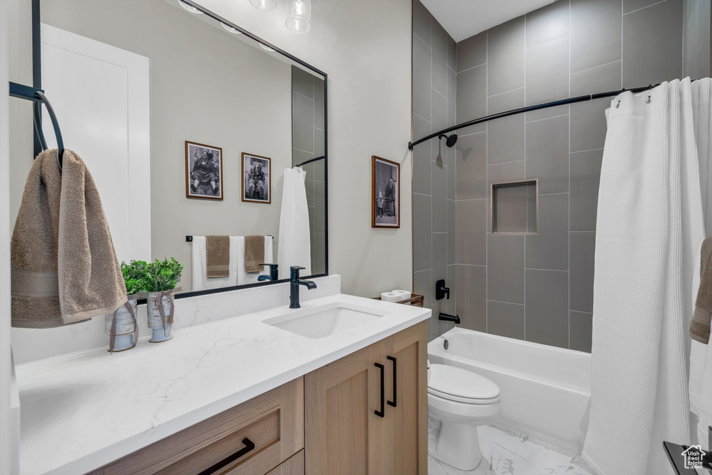 Full bathroom with marble finish floors, shower / bath combination with curtain, vanity, and toilet