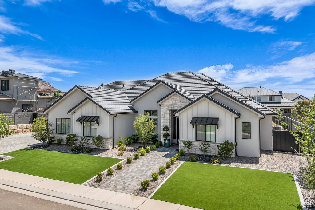Modern farmhouse featuring stone siding, board and batten siding, and a tiled roof