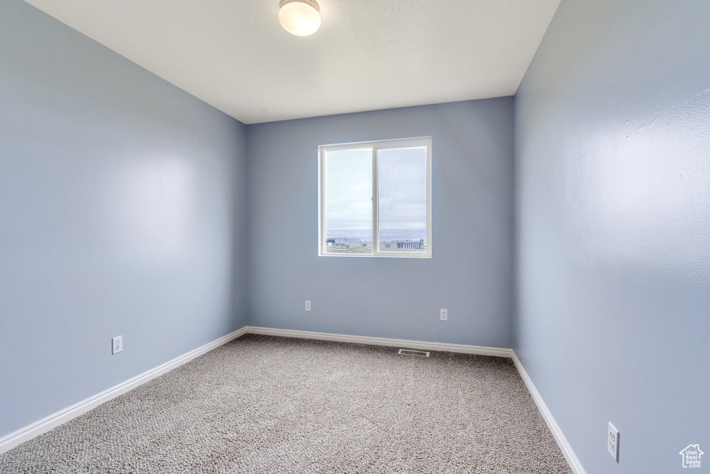 Carpeted empty room featuring baseboards