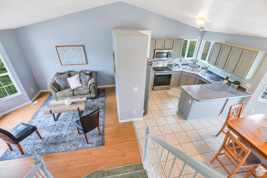 Living area featuring vaulted ceiling, light wood finished floors, and baseboards