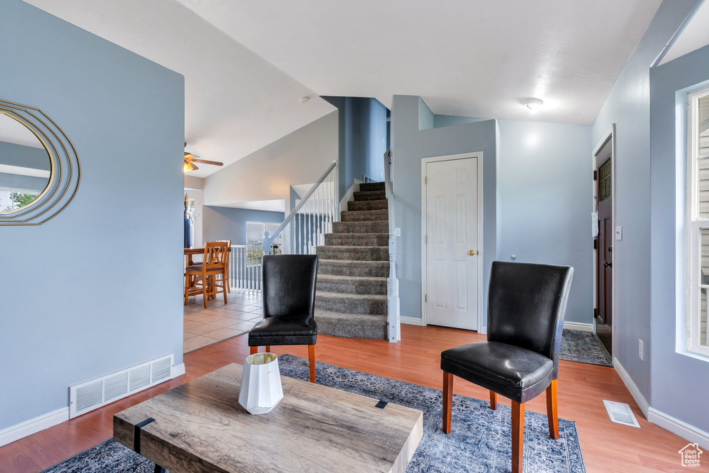 Living room with stairway, ceiling fan, lofted ceiling, baseboards, and wood finished floors